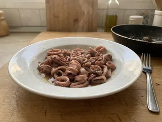 Calamares en rodajas y patas salteados con ajo, cebolla, vino blanco y perejil, en una sartén